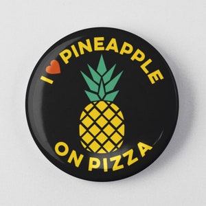 May include: A round, black button with the text "I LOVE PINEAPPLE ON PIZZA" in yellow. A yellow pineapple with green leaves is in the center, and a red heart is above the word "PINEAPPLE".
