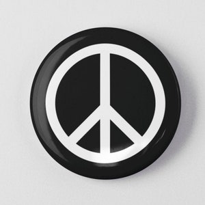 May include: A black and white peace sign button. The peace sign is white and is centered on a black circle.