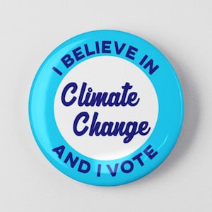 May include: A blue and white button with the text "I believe in Climate Change and I Vote" in white and blue lettering.