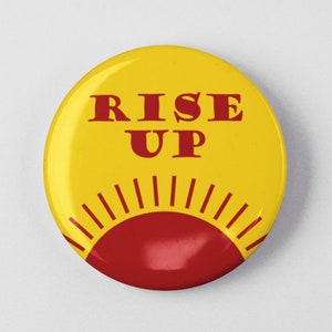 May include: Yellow button with the text "RISE UP" in red letters. A red sun with rays is at the bottom of the button.