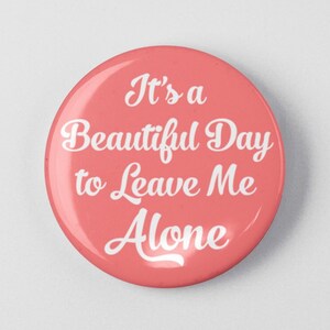 May include: A pink button with white text that reads "It's a Beautiful Day to Leave Me Alone."