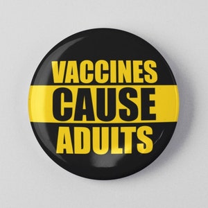 May include: A black and yellow button with the text "Vaccines Cause Adults" printed on it.