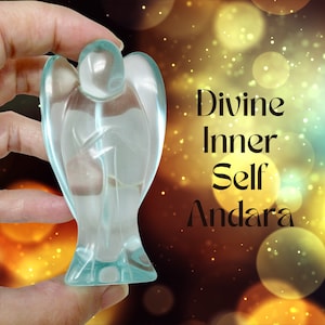 May include: A translucent, pale blue angel figurine. The angel has outstretched wings and is held in a hand. The background is a bokeh of gold and yellow lights. Text on the right reads "Divine Inner Self Andara."