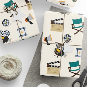 May include: White wrapping paper with a repeating pattern of film reels, clapperboards, director's chairs, and megaphones. The paper is tied with twine and a white tag.