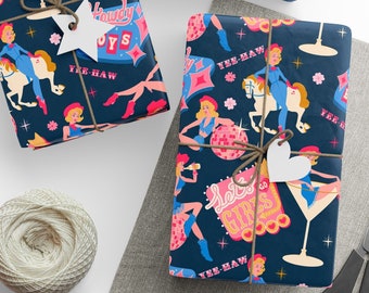 May include: Gift wrap with a navy blue background featuring a retro cowgirl design in pink, blue, and white. The wrapping paper is tied with twine and adorned with star and heart-shaped tags. A ball of twine and scissors are also visible.