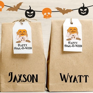 Könnte beinhalten: Zwei braune Papiertüten mit den personalisierten Namen "Jaxson" und "Wyatt" auf der Vorderseite. Jede Tüte hat ein Etikett mit einer Cartoon-Kürbis, die ein Geisterkostüm trägt, und dem Text "Happy Howl-O-Ween".