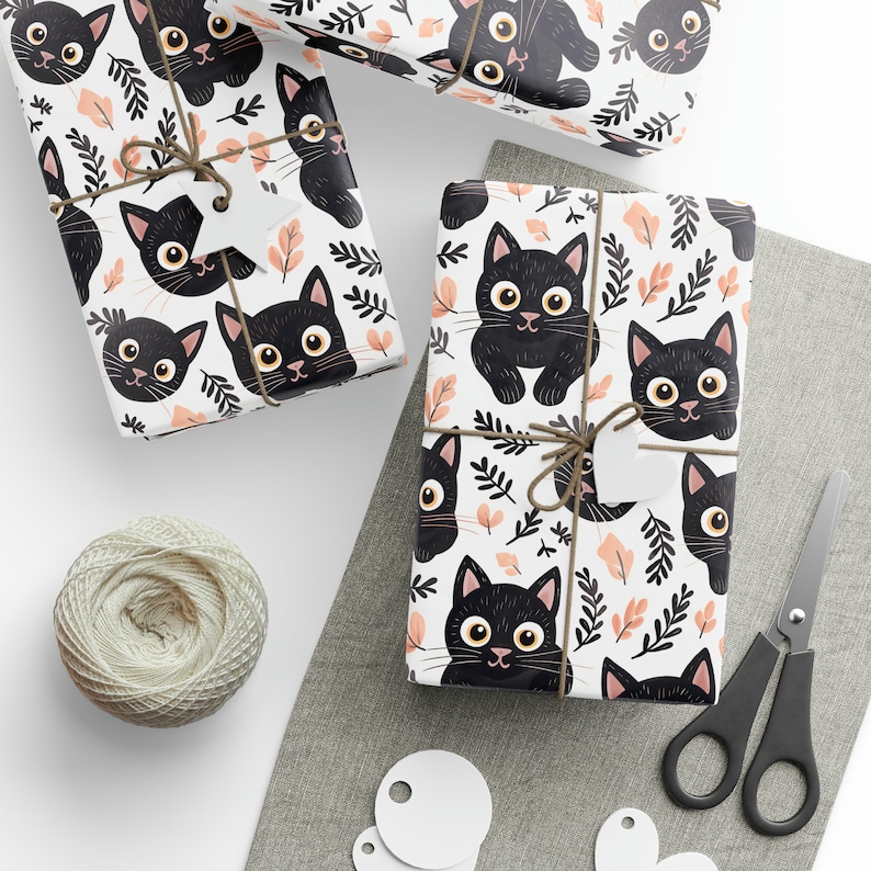 K&ouml;nnte beinhalten: Mehrere Geschenkverpackungen mit einem sich wiederholenden Muster aus schwarzen Katzen mit gelben Augen und rosa Nasen auf wei&szlig;em Hintergrund mit pfirsichfarbenen Bl&auml;ttern und schwarzen Zweigen. Die Geschenke sind mit Bindfaden gebunden und haben leere Anh&auml;nger. Ein Kn&auml;uel Bindfaden und eine Schere sind ebenfalls vorhanden.