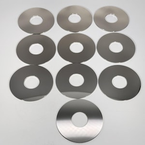 Peut inclure: Un ensemble de dix disques métalliques circulaires identiques, chacun présentant une surface argentée lisse et réfléchissante avec une découpe circulaire centrale. Les disques sont disposés en grille, mettant en valeur leur forme uniforme.