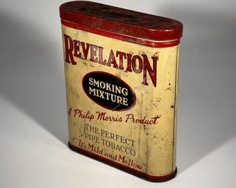 May include: A vintage rectangular metal tobacco tin with a cream-colored body and a red lid. The front features the text REVELATION SMOKING MIXTURE, A Philip Morris Product, THE PERFECT PIPE TOBACCO, and It's Mild and Mellow in red and black.