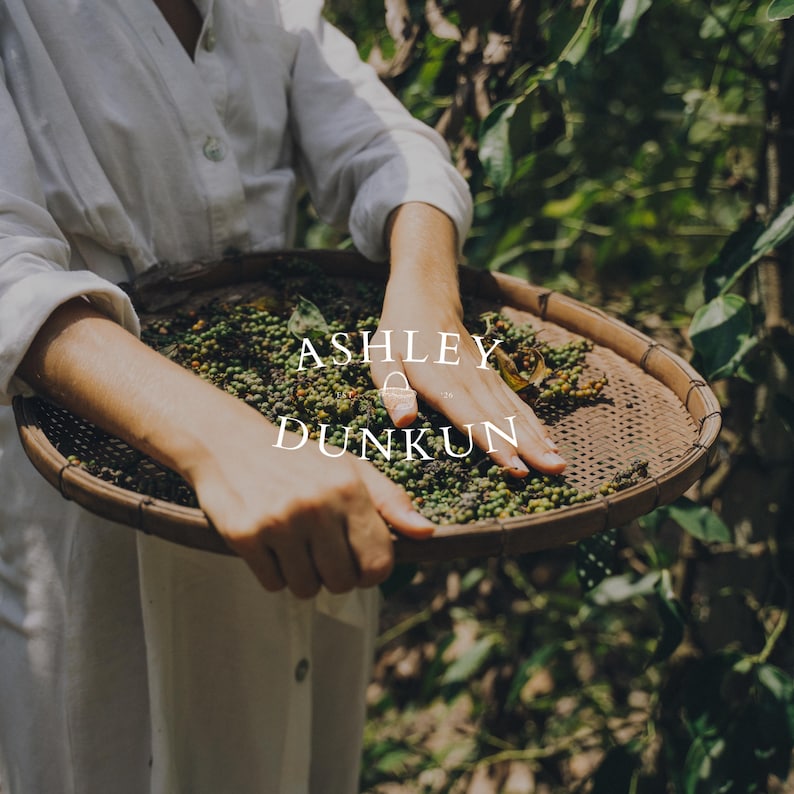 May include: A person holding a woven tray filled with green peppercorns. The tray is round and made of natural fibers. The text "ASHLEY DUNKUN" is displayed in white, centered on the image.