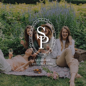 May include: Three people sitting on a plaid blanket in a garden, holding wine glasses. One wears a peach top, one a green dress, and one a white eyelet blouse with tan trousers. A logo with the text SP SAVANNAH PHOTOGRAPHY is centred.