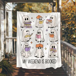 May include: White throw blanket featuring a design of nine ghosts reading books. The text "My Weekend is Booked" is printed at the bottom of the blanket.