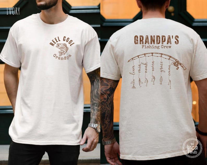 May include: An ivory t-shirt featuring brown graphics. The front displays a fish illustration with the text "REEL COOL Grandpa". The back shows a fishing rod graphic with the text "GRANDPA'S Fishing Crew" and names hanging from the line.