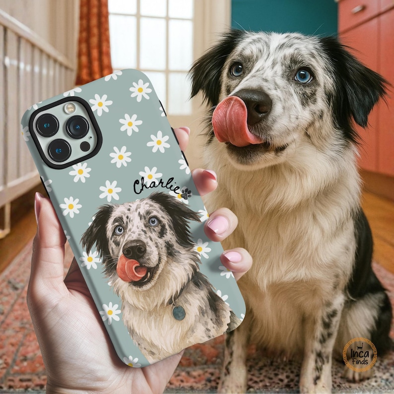 May include: A light blue smartphone case featuring a repeating white daisy pattern and a custom illustration of a speckled dog with blue eyes and a pink tongue. The name Charlie is printed in black script above the dog illustration.