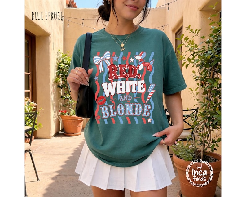 May include: Teal t-shirt featuring the text "RED, WHITE, AND BLONDE" in red and white, with patriotic graphics. The shirt is worn with a white pleated skirt. The words "BLUE SPRUCE" are at the top left.