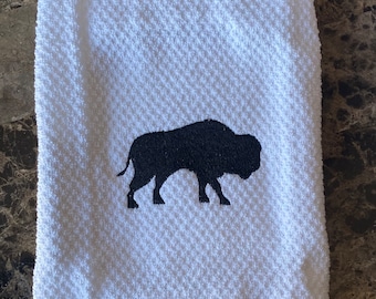 May include: White kitchen towel with a black embroidered buffalo silhouette and gray stripes at the bottom.