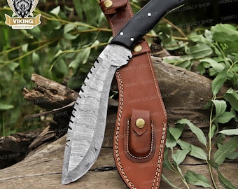 May include: A Damascus steel knife with a black handle and a brown leather sheath. The blade has a unique pattern and a serrated edge. The sheath has a button closure. The knife is designed for outdoor use.