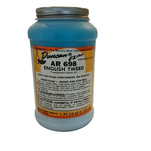 May include: A jar of Duncan AR 698 English Tweed ceramic glaze. The jar has a silver lid and a label with the product name and instructions. The glaze is a light blue color and is 1 pint (16 fl oz / 473 ml).