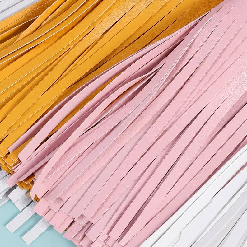 Pu&ograve; includere: Primo piano di una frangia multicolore con fili gialli, rosa e bianchi. La frangia &egrave; in pelle e probabilmente viene utilizzata a scopo decorativo.