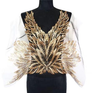Peut inclure: Applique en feuille d'or sur fond noir. L'applique présente un grand motif complexe de feuilles et de branches.