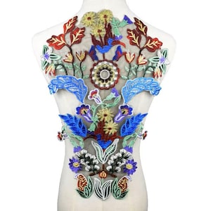 Pode incluir: Uma aplicação de bordado floral colorida com flores azuis, vermelhas, verdes, amarelas e brancas em um tecido de malha transparente. A aplicação é perfeita para adicionar um toque de elegância a roupas, bolsas ou projetos de decoração de casa.