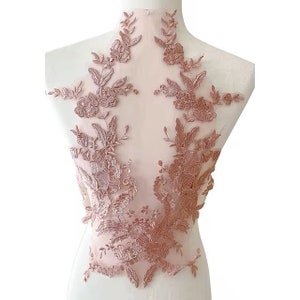 May include: A delicate pink lace applique featuring floral designs. The lace is on a sheer mesh fabric and is ideal for adding a touch of elegance to any project.