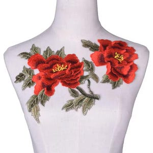 Puede incluir: Aplique de flores bordadas rojas con hojas verdes. Este diseño floral es perfecto para agregar un toque de elegancia a la ropa, los bolsos o los proyectos de decoración del hogar.