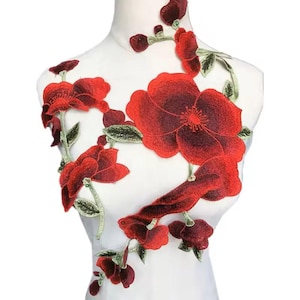 May include: Red embroidered floral applique with green leaves. The applique features a large red flower with a darker red centre and smaller red flowers.