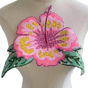 May include: Pink and yellow sequined hibiscus flower applique with green sequined leaves.