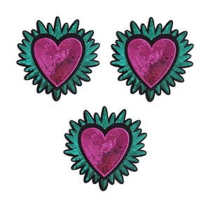 Puede incluir: Tres parches en forma de corazón con un centro rosa con lentejuelas y un borde verde turquesa con púas. Los parches están dispuestos en un patrón triangular sobre un fondo blanco. Adecuado para ropa o proyectos de manualidades.
