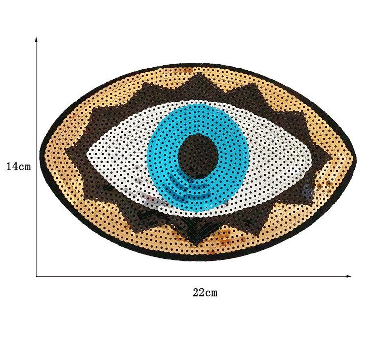 May include: An oval-shaped sequined patch in the shape of an eye. The eye features a blue iris, white sclera, and a brown and gold sequined border. The patch measures approximately 9 inches wide and 5.5 inches tall.
