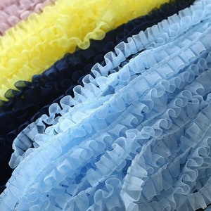 Könnte beinhalten: Nahaufnahme einer hellblauen Rüschenborte. Die Borte ist aus einem weichen, durchsichtigen Stoff gefertigt und hat einen zarten, femininen Look.