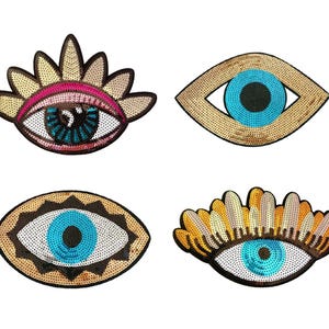 Könnte beinhalten: Vier dekorative Augen-Patches mit Pailletten-Details. Die Patches weisen verschiedene Designs auf, darunter blaue und schwarze Pupillen, goldene und rosa Akzente sowie komplizierte Muster. Ideal, um Kleidung oder Accessoires eine einzigartige Note zu verleihen.