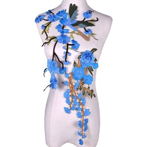 Könnte beinhalten: Blaue gestickte Applikation mit einem Vogel, der auf einem Zweig mit blauen Blumen und Blättern sitzt. Die Applikation ist perfekt, um Kleidung, Taschen oder Heimtextilien mit einem Hauch von Eleganz zu verschönern.