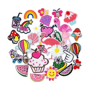Könnte beinhalten: Eine Sammlung bunter Bügelbilder mit verschiedenen Designs, darunter ein Regenbogen, ein Cupcake, ein Heißluftballon, ein Flamingo, ein Kaktus, eine Wassermelone, ein Pilz, ein Rollschuh, eine Gänseblümchen, ein Herz, eine Biene, ein Eis am Stiel, eine Muschel, ein Diamant, ein Stern, ein Mädchen, ein "Nimm mich mit"-Becher und ein Smiley.