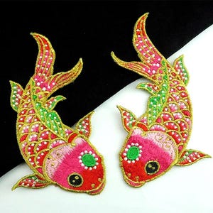 Puede incluir: Dos peces koi bordados en rosa y rojo con detalles en verde y dorado. Los peces están mirando en direcciones opuestas y tienen un patrón de escamas detallado.