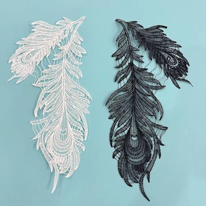 Peut inclure: Deux appliques en dentelle en forme de plumes, l'une blanche et l'autre noire. Les plumes sont ornées de dentelles complexes et ont un aspect délicat et féminin.