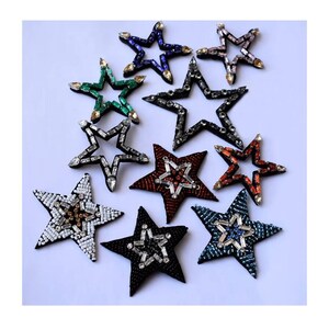 May include: Assortment of ten star-shaped embellishments with various colours and designs. The embellishments are made of fabric and decorated with beads and rhinestones.