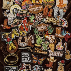 May include: A selection of embroidered patches with a Western theme. Designs include cowboy hats, boots, cacti, horses, and the text "WANTED", "HOWDY", "YEEHAW", and "NORTH SIDE COWECY". The patches are in various colours and shapes.