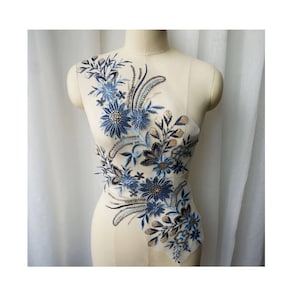 以下が含まれることがあります： 青い花柄のアップリケにビーズのアクセントが施されています。この繊細なレースの装飾は、衣服、アクセサリー、または家の装飾プロジェクトにエレガントなタッチを加えるのに最適です。