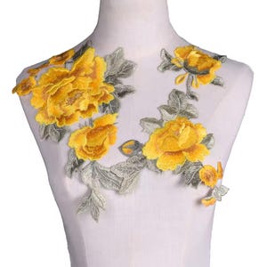 May include: Yellow floral applique with delicate embroidery details. The applique features a cluster of yellow flowers with green leaves and stems. This applique is perfect for adding a touch of elegance to clothing, accessories, or home decor projects.
