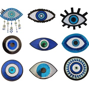 Könnte beinhalten: Eine Sammlung von neun dekorativen Aufnähern und Ornamenten in Augenform mit verschiedenen Farbgebungen in Blau, Weiß und Schwarz. Die Designs umfassen kreisförmige und mandelförmige Motive mit Paillettentexturen, Perlenfransen und markanten grafischen Umrandungen.
