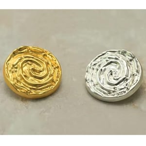 Pode incluir: Dois botões redondos decorativos com um design de redemoinho e textura. Um botão é dourado e o outro é prateado.