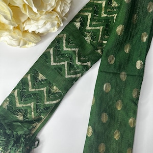 Puede incluir: Una bufanda verde con lunares dorados y un patr&oacute;n geom&eacute;trico dorado. La bufanda tiene flecos en un extremo.