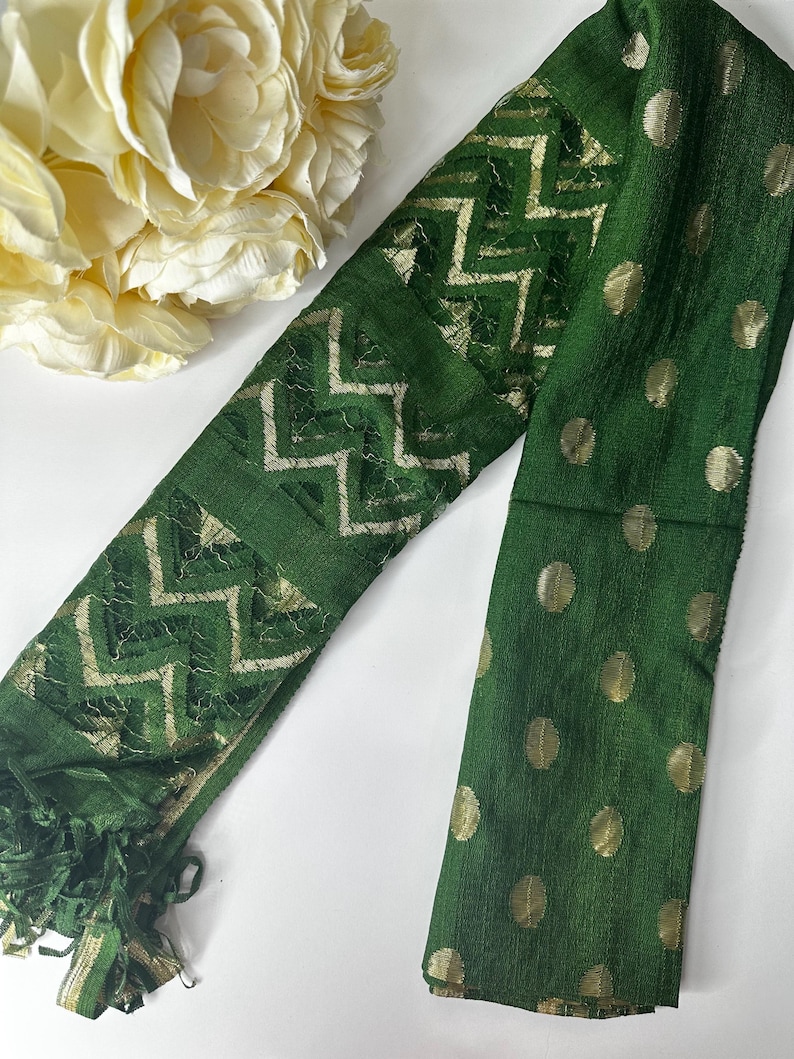 Puede incluir: Una bufanda verde con lunares dorados y un patr&oacute;n geom&eacute;trico dorado. La bufanda tiene flecos en un extremo.