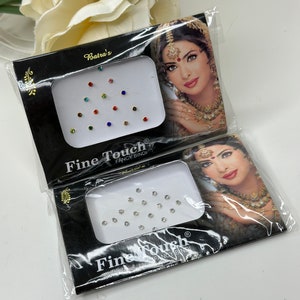 May include: Two packs of adhesive rhinestones for the face. One pack has clear rhinestones and the other has colorful rhinestones. Both packs have a woman's face on the front with the text "Fine Touch Fancy Bindi" on the bottom.