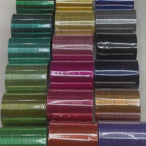 May include: A set of 18 colorful metal bangles, packaged in clear plastic. The bangles are arranged in rows of three, with each row featuring a different color. The colors include green, gold, blue, gray, purple, pink, orange, and silver.