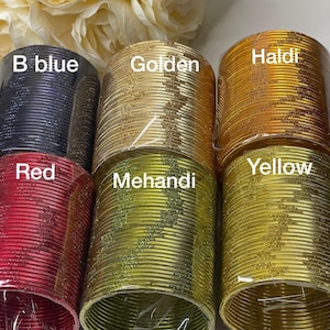 May include: Stacks of colorful bangles in shades of blue, red, gold, yellow, and green. Each stack is labeled with a color name: B blue, Red, Golden, Haldi, Mehandi, and Yellow. The bangles are wrapped in clear plastic.