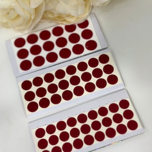 May include: Three sheets of red round adhesive stickers on white backing. Each sheet has 24 stickers.