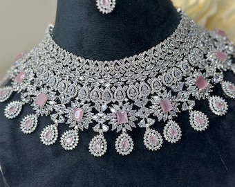 May include: A silver and pink bridal necklace set with a choker style necklace and matching earrings. The necklace features large, clear cubic zirconia stones and pink stones.